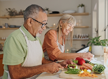 Happy older couple chopping vegetables