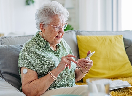 Senior diabetic woman on couch checking phone